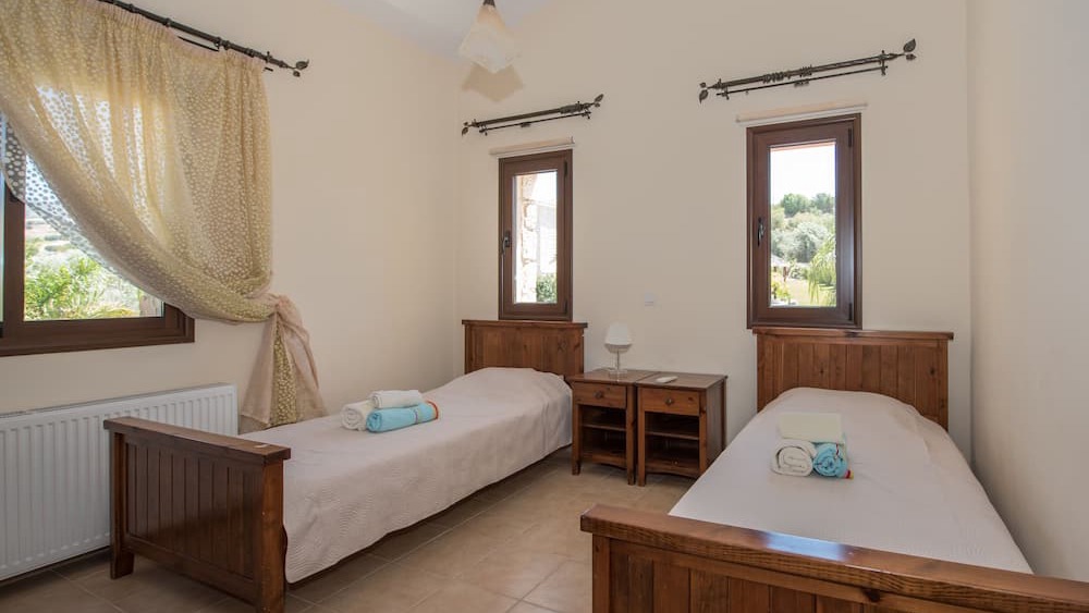 A twin bedroom with wooden furniture and country views