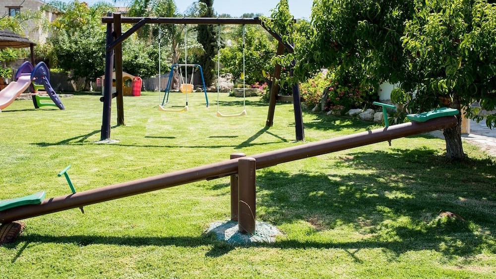 Swings and a seesaw in the garden play space