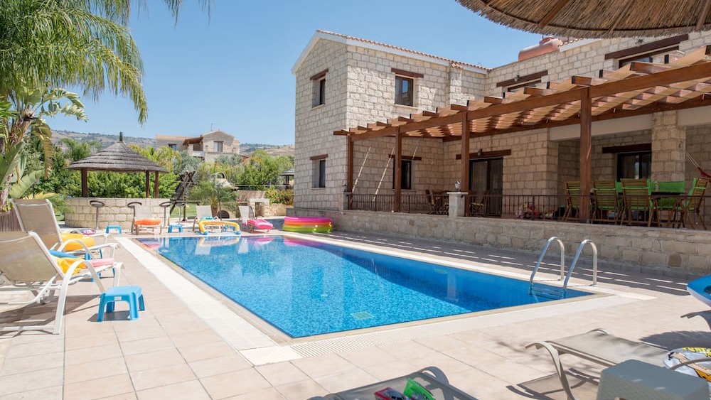 The stone facade of Stephanie Villa beside its private pool and timber pergola