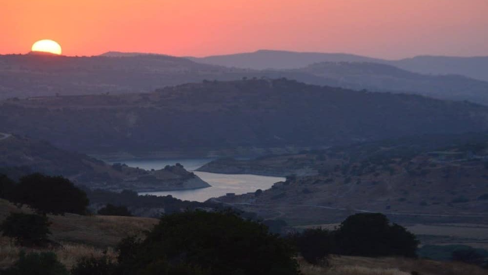 Sunset over the rolling hills and a reservoir in the countryside near Simou